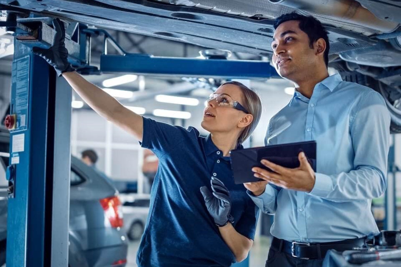 service technicians inspecting a car under service lift