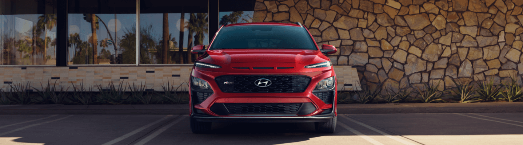 Front view of red Hyundai Kona parked in front of a building